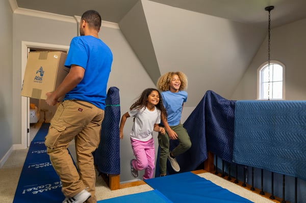 Two children running upstairs to pick out their bedrooms while Atlas movers unload boxes 