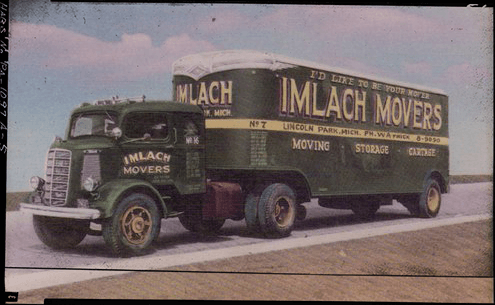 Old photograph of a green moving truck with the words IMLACH MOVERS painted on the side of the trailer and cabin door.